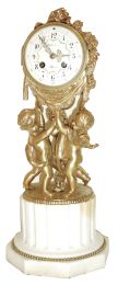 Samuel Marti, Paris, France, mantel clock, three gilt putti supporting the drum form case, the top draped with a garland of roses, gilt bezel with convex glass, Arabic numeral white enamel dial with polychrome enamel floral festoons, fancy gilt hands, all resting on a white marble fluted plinth with octagonal base, 8 days, time and strike, pendule a Paris movement, c1900