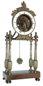 France, gilt bronze mantel timepiece, the oblong base with beaded molding and on turned feet, supporting four slender, tapered columns with reeded, urn form bases, and surmounted with turned urn form finials, the portico supporting the, 8 days, timepiece movement and skeletonized, Roman numeral white enamel dial, silk suspended pendulum with gilt Helios mask, and decorative pierced and chased gilt hands, c1800