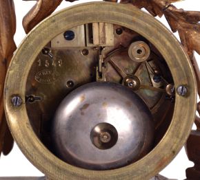 Japy Freres, Paris, France, figural mantel clock, 8 day time and strike, count wheel and bell, spring driven movement with floral themed ceramic dial and insets in a gilt spelter case featuring a seated female figure surrounded by symbols of art and science including a pitcher, gear, paintbrush & pallet, books, steam engine, anvil, spyglass, and square.
