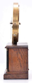 German, Hamburg - American Clock Co., "La Mysterieuse" desk or table clock, rectangular oak base supporting the Arabic numeral transparent dial with brass bezel, movement contained in the base, and driving a second invisible disc to which the motion work is attached, thus driving the hands