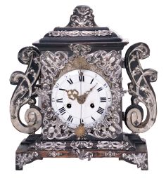 Europe, 18th century, bracket or shelf clock with cow tail pendulum, ebonized wooden case with applied moldings and laden with leaf and scroll, repousse silver ornaments, and case sides with applied scroll ornaments Roman numeral white enamel dial with raised chapter and concave center, fancy pierced and engraved brass hands, brass time and strike movement probably of two day duration, with verge escapement, and engraved, star shaped pendulum swinging in front of the dial