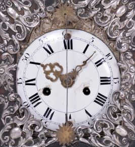 Europe, 18th century, bracket or shelf clock with cow tail pendulum, ebonized wooden case with applied moldings and laden with leaf and scroll, repousse silver ornaments, and case sides with applied scroll ornaments Roman numeral white enamel dial with raised chapter and concave center, fancy pierced and engraved brass hands, brass time and strike movement probably of two day duration, with verge escapement, and engraved, star shaped pendulum swinging in front of the dial
