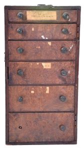 Assorted clock and watch tools in six drawer wood cabinet. Tools include a small bench vise, alcohol torches, truing calipers, pliers, tongs, files, hammers, screw plates, pin vises, screwdrivers, tweezers, 10 WW lathe collets, and other useful hand tools.