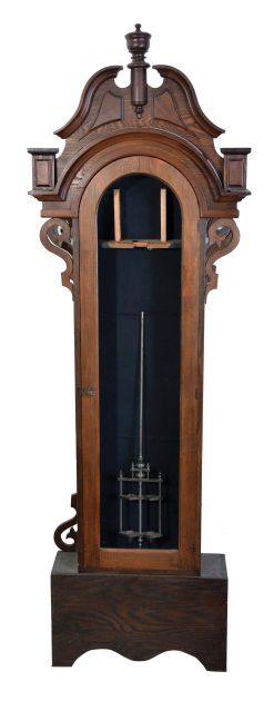 Tall Clocks- 3 (Three): The first, a late 19th century pinwheel regulator, oak case with round top and removable crest, sides with applied scroll ornament, Roman numeral white enamel dial, blued steel hands, 8 day weight driven timepiece movement with heavy gridiron pendulum, the next an 18th century European tall clock with walnut veneer case, molded and paneled base below trunk door with glazed oculus, bonnet with canted corners, 8 day, time and strike movement, and sheet iron dial with applied chapter ring, the last by T. Gate, Carlisle, oak case with flat top bonnet, brass composite dial, and 8 day, time and strike movement, together with a nickel plated regulator pendulum,
