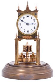 German 400-Day or Anniversary clock: (Retailer =Kuehl Clock Company, Chicago), time only spring driven movement torsion pendulum movement by Gustav Becker of Freiburg, Germany with disc pendulum in polished brass case under glass dome, c1910.