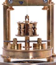 German 400-Day or Anniversary clock: (Retailer =Kuehl Clock Company, Chicago), time only spring driven movement torsion pendulum movement by Gustav Becker of Freiburg, Germany with disc pendulum in polished brass case under glass dome, c1910.