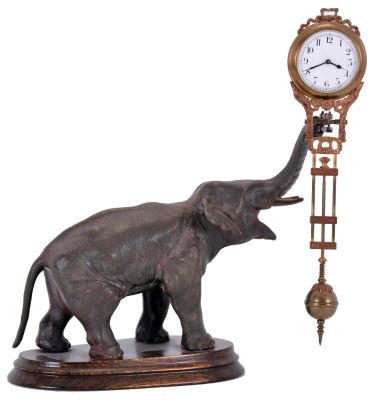 Junghans, Germany, elephant model swinging clock, patinated figure of an elephant mounted to a molded beechwood base, the 8 day swinging timepiece held aloft at the end of his trunk, clock case with gilt and patinated surfaces, Arabic numeral white enamel dial signed "Junghans Germany" below 6:00, blued steel hands, 8 day time only movement