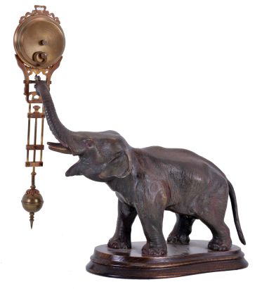 Junghans, Germany, elephant model swinging clock, patinated figure of an elephant mounted to a molded beechwood base, the 8 day swinging timepiece held aloft at the end of his trunk, clock case with gilt and patinated surfaces, Arabic numeral white enamel dial signed "Junghans Germany" below 6:00, blued steel hands, 8 day time only movement