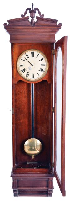 New York Standard Watch Co., Jersey City, New Jersey, electric hanging regulator, walnut case with molded door and base, Roman numeral painted dial with brass bezel, in line movement with Hipp toggle, pendulum with ebonized wooden rod and heavy brass clad ball