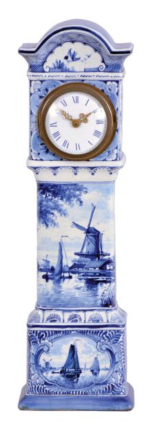 France, ceramic miniature tall clock, the earthenware case with blue, freehand decoration on a white ground, depicting harbor scenes with windmills on the trunk and base, with naturalistic ornament on the bonnet and base sides, Roman numeral white enamel dial with gilt Louis XV style hands, 8 day timepiece movement with cylinder platform, case bottom with makers mark