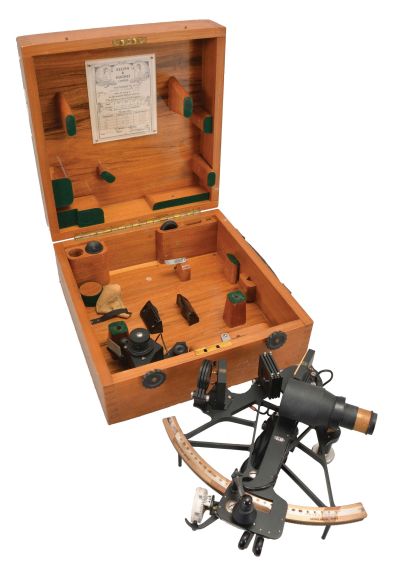 Kelvin & Hughes Ltd., London, 7 inch radius sextant, pierced black metal frame, signed brass arc with inset silvered arc graduated from -5 to 125, index arm with K&H logo, micrometer drum vernier adjustment, index lamp, multiple shades for index and horizon mirrors, sighting telescopes, auxiliary lamp, and black plastic handle with battery compartment all in a finger-jointed case with certificate under the lid dated 1955.
