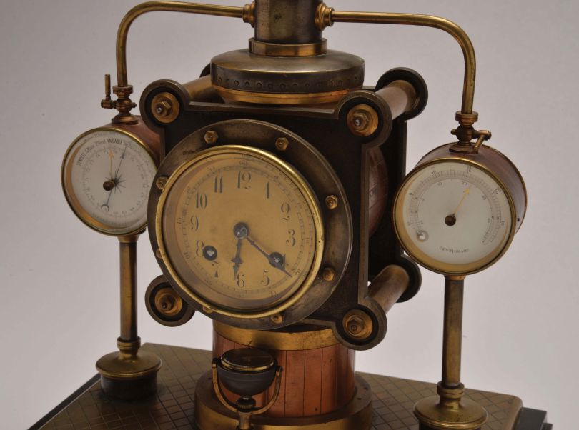 France- Andre Romain Guilmet, a rare Industrial steam boiler compendium with centrifugal governor pendulum, the stepped black slate base supporting a compass on a decorative stand, before a boiler with gilt and patinated silver surfaces and ribbed, copper base matching the clock case, the top having a cylindrical chamber with vent pipes attached to gauge form, flanking, white dialed thermometer and barometer, and concealing the helical suspension spring controlling the centrifugal governor form pendulum, Arabic numeral gilt dial, blued steel distaff hands, and 8 day pendule de Paris time and strike movement with Guilmet