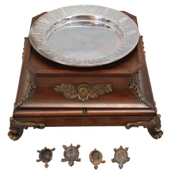 A. Cadot, Place Dauphine, Paris, a mahogany, gilt bronze mounted, floating turtle mystery clock, the case with square base on cast scroll feet, the upper portion with incurved sides with bronze mounts and molded top, supporting a water filled pewter bowl, the rim with engraved roman numerals, and arabic 15 minute markers, the turtle floating, and indicating the time, driven by a magnetic ring attached to the timepiece movement with lever platform concealed in the base, the back plate signed Samuel Marti, the front with Cadot