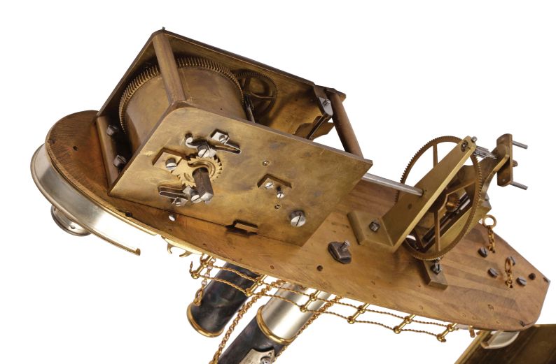 France, possibly Andre Romain Guilmet, a rare silvered and gilt brass, automated, battleship form compendium, the vessel bow with ram, fourteen cannon, and four anchors, the gilt deck with capstan containing a compass, two revolving gun turrets, one having an 11 jewel lever timepiece, with roman numeral silvered dial and blued steel trefoil hands, the other with aneroid barometer, also with silvered dial, the stacks with mounted Fahrenheit and Centigrade thermometers, the stern with ships wheel and flag, above the articulated rudder and revolving propeller, a movement concealed in the ship