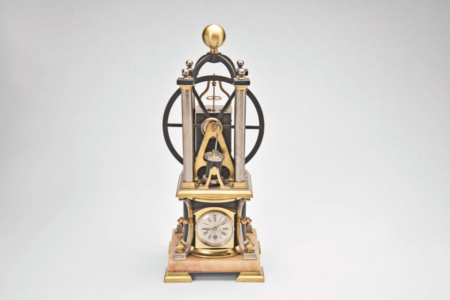 France, possibly Andre Romain Guilmet, a rare, automated, oscillating cylinder steam engine timepiece, the honey onyx square base on gilt feet, and supporting the black bronze boiler with cove molded top and bottom, below the engine itself, comprised of a large, A frame supported, spoked flywheel, connected to a rocking cylinder through a cranked linkage, the movement powering the automation contained in a black enclosure behind the engine, the enclosure top with a rotating governor in a bell shaped frame behind the wheel, surrounded by four silvered columns, and surmounted by an X shaped, arched frame with central spherical finial, the 11 jewel lever platform movement with Roman numeral silvered dial and blued steel Breguet style hands