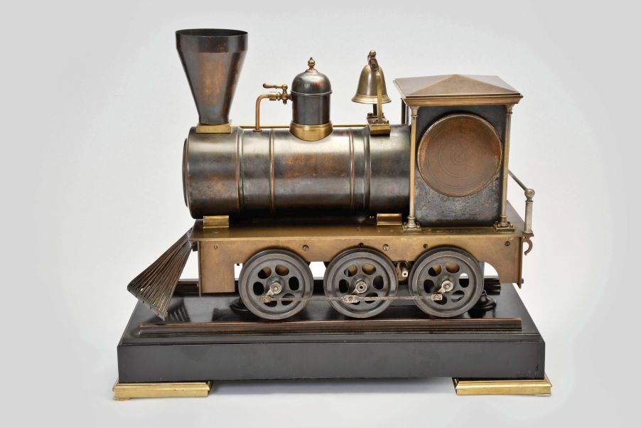 France, a rare, automated, patinated bronze locomotive form compendium, the stepped, black slate base on gilt feet with patinated rails below the large, steam locomotive, the darker surfaces highlighting the nickel, brass, and copper appointments, the engine front with cow catcher, the boiler with aneroid barometer, bell, steam dome with valve and flared stack with centigrade thermometer, the cab with shallow pitched roof, slender columns at the corners, and containing the clock and dial, a concealed movement in the base providing power to drive the six wheels, connecting rods, and piston, roman numeral brass dial, blued steel Breguet style hands, and 8 day, two train pendule de Paris movement