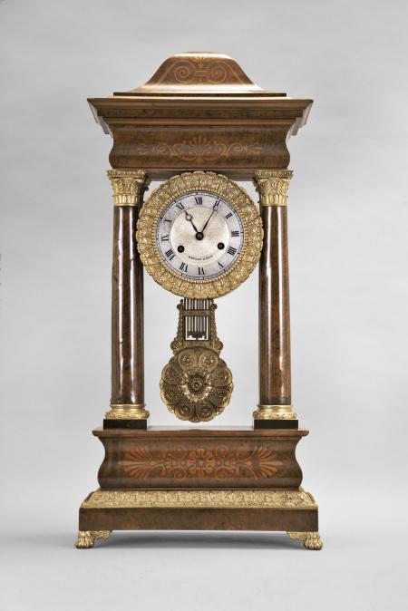 France, portico clock, 8 day, time and strike, round spring driven movement in a figured hardwood veneer case with satinwood inlay on the front, cast leaf moldings on the base, columns, pendulum, and bezel, roman numeral silvered dial with guilloché center, blued steel Breguet style hands