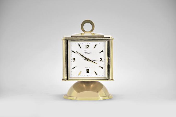 Clocks- 2 (Two) Swiss Desk: (1) Switzerland, for Tiffany & Co., New York, NY, weather station, battery powered timepiece with calendar, barometer, hygrometer, thermometer, all with silvered dials in a brass case with swivel base, c1970; (2) Jaeger-LeCoultre, Switzerland, desk clock, 8 day, time only, spring driven balance wheel movement in a round clear acrylic and lacquered brass case, c1985.