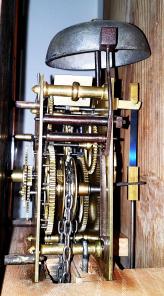 England, tall clock, 30 hour, time and strike, weight driven bell strike movement in an American-made walnut case with flat top, painted metal dial with floral elements, pierced brass hands.