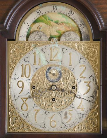 Unknown, England, hall clock, 8 day, time and strike with Westminster chimes, three train weight driven brass movement with deadbeat escapement in a walnut case with molded base, glazed door, and hood with broken arch, arched dial with silvered chapter ring with applied brass numerals, pierced and engraved spandrels and dial center, moon phase dial, chime / silent selector, and subsidiary seconds dial.