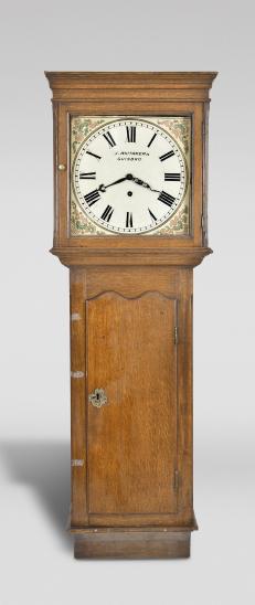 J. Whitaker, Guisborough, North Yorkshire, England, long case wall clock, 8 day, time only, weight driven brass movement in an oak case with signed painted metal dial and black steel hands.