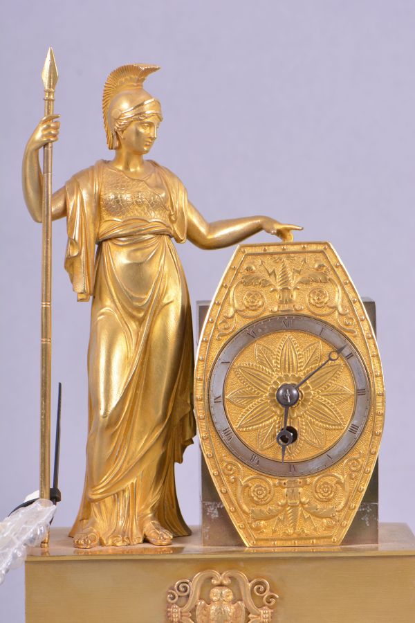 France, mantel timepiece, 8 day, time only, spring driven brass movement with thread suspension in a stepped, molded brass base upon which stands the cast gilt figure of the goddess Athena holding a spear in one hand, the other hand holding a shield within which is set a silvered chapter ring with roman numerals, blued steel Breguet style hands.