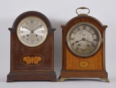 Clocks- 2 (Two) mantel: (1) Pearce & Sons Ltd., Leeds, England, mantel clock, 8 day, time and strike spring driven movement in a small bracket clock case with figured mahogany and inlaid flower design, roman numeral two-piece silvered dial, black steel hands, c1910; (2) Waltham Clock Co., Waltham, Mass., for Bigelow, Kennard & Co., Boston, mantel clock, 8 day, time and strike, spring driven balance wheel movement in a mahogany case with broken arch top and butterfly inlay, arabic numeral silvered dial, blued steel hands, c1920.