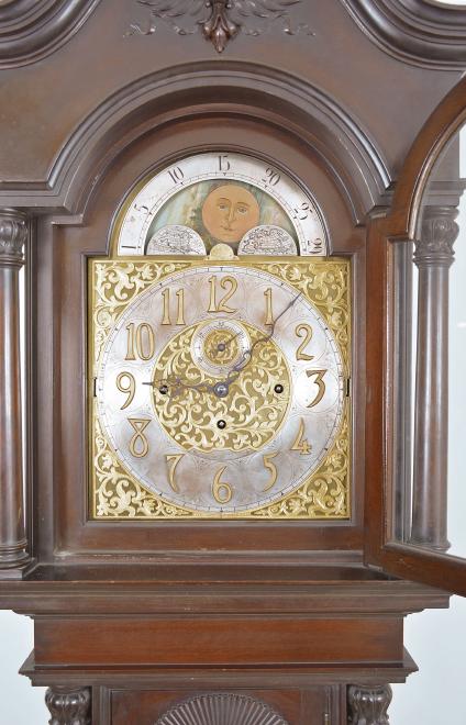 Herschede Hall Clock Co., Cincinnati, Ohio, hall clock, 8 day, time, strike and chime on five tubular bells, three brass weight driven movement in a mahogany case with arched top with central carved cartouche and applied carvings, full columns with carved capitals flanking hood door over trunk door with beveled glass and carved fan top flanked by full columns with carved capitals on base with large applied carving resting on paw feet. The brass dial has silvered chapter ring, subsidiary seconds, strike / silent and chime / silent discs, engraved brass spandrels and dial center, applied brass numerals and moon phase indicator.