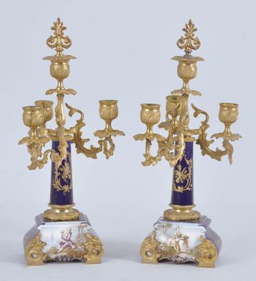 France for Bawo & Dotter, Importer, New York, USA, New York, NY, three piece mantel garniture set, 8 day, time and strike, spring driven pendule de Paris movement in a ceramic case with blue glaze and applied gilt ornaments, the front with neoclassical romantic scene signed "Petit", the dial flanked by two full ceramic columns with gilt bases and capitals, arabic numeral white enamel dial with polychrome garlands, pierced brass hands, and matching set of candelabra both with blue glaze and painted scenes.



