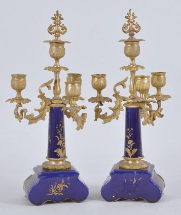 France for Bawo & Dotter, Importer, New York, USA, New York, NY, three piece mantel garniture set, 8 day, time and strike, spring driven pendule de Paris movement in a ceramic case with blue glaze and applied gilt ornaments, the front with neoclassical romantic scene signed "Petit", the dial flanked by two full ceramic columns with gilt bases and capitals, arabic numeral white enamel dial with polychrome garlands, pierced brass hands, and matching set of candelabra both with blue glaze and painted scenes.



