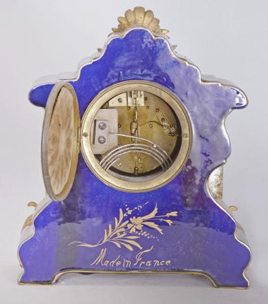 France for Bawo & Dotter, Importer, New York, USA, New York, NY, three piece mantel garniture set, 8 day, time and strike, spring driven pendule de Paris movement in a ceramic case with blue glaze and applied gilt ornaments, the front with neoclassical romantic scene signed "Petit", the dial flanked by two full ceramic columns with gilt bases and capitals, arabic numeral white enamel dial with polychrome garlands, pierced brass hands, and matching set of candelabra both with blue glaze and painted scenes.



