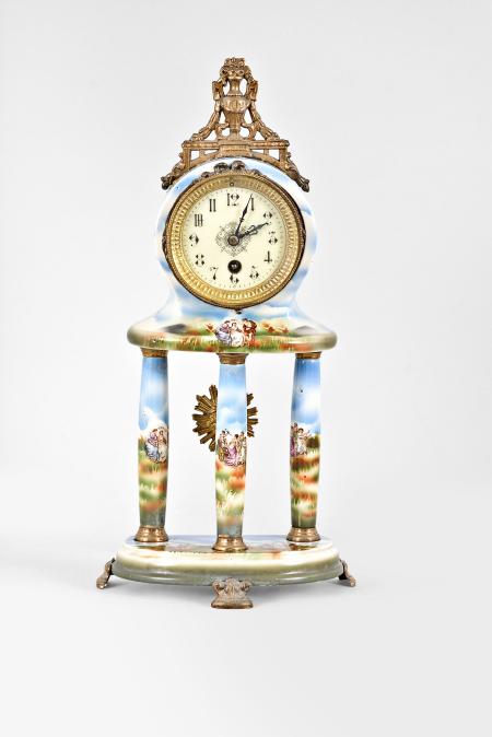 Japy Frères & Cie, Paris, France, mantel timepiece, 8 day, time only, spring driven movement in a polychrome ceramic case, the base on three cast metal feet, three columns supporting the clock decorated with mythical scenes and topped by a cast urn crest piece, arabic numeral white enamel dial and black steel hands.