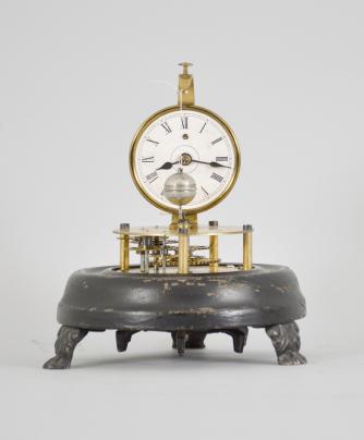 E.N. Welch Mfg. Co., Forestville, Conn., "Briggs Rotary" novelty timepiece with a 30 hour, spring driven brass movement with conical pendulum, 2 inch papered dial with roman numerals, black steel spade hands, all on a black painted wood base with cast metal paw feet and under a small glass dome. These were manufactured under John C. Brigg