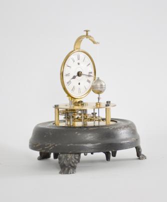 E.N. Welch Mfg. Co., Forestville, Conn., "Briggs Rotary" novelty timepiece with a 30 hour, spring driven brass movement with conical pendulum, 2 inch papered dial with roman numerals, black steel spade hands, all on a black painted wood base with cast metal paw feet and under a small glass dome. These were manufactured under John C. Brigg