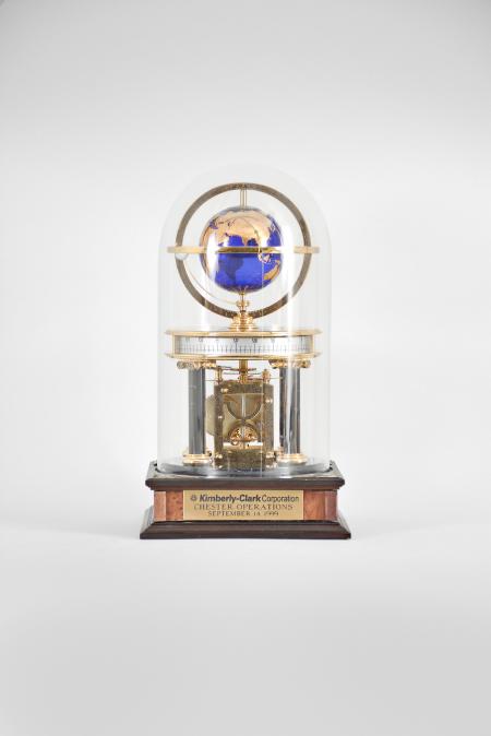 Hermle & Sohn, Germany, for the Franklin Mint, "Royal Geographical Society Millennium Clock", 8 day, time and rotating planets, spring driven movement with annular time display on a molded wood base with four black stone columns supporting a polished brass frame, gilt blue glass earth sphere and white polished stone orbiting moon, all under a glass dome.