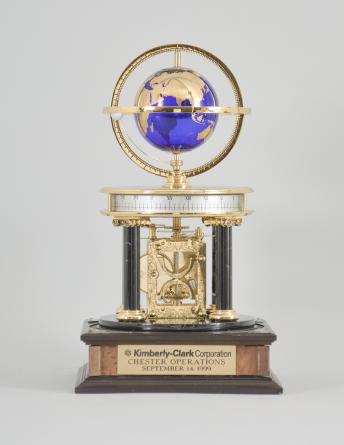 Hermle & Sohn, Germany, for the Franklin Mint, "Royal Geographical Society Millennium Clock", 8 day, time and rotating planets, spring driven movement with annular time display on a molded wood base with four black stone columns supporting a polished brass frame, gilt blue glass earth sphere and white polished stone orbiting moon, all under a glass dome.