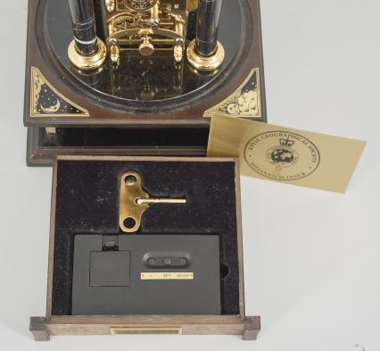 Hermle & Sohn, Germany, for the Franklin Mint, "Royal Geographical Society Millennium Clock", 8 day, time and rotating planets, spring driven movement with annular time display on a molded wood base with four black stone columns supporting a polished brass frame, gilt blue glass earth sphere and white polished stone orbiting moon, all under a glass dome.