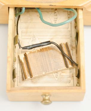 Clocks- 2 (Two) Electromechanical shelf clocks (1) England, mantel clock, battery powered movement electromagnet pendulum encircling a segment of permanent magnet, skeletonized brass movement on two posts mounted to a molded wood base, arabic numeral silvered dial, black steel hands, all under an clear acrylic box with arched top, c1935; (2) Barr Mfg. Corp., Weedsport, NY, mantel clock, electric battery movement in a brass frame, silvered dial with subsidiary seconds, black steel hands, all under a glass dome resting on a turned wood base, c1938.