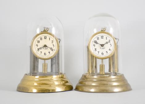 Clocks- 2 (Two) Mountain State Electrical Co., Wheeling, W. Virginia, "No-Key" clocks, weight driven brass movements with battery powered automatic winding, brass bases, arabic numeral white celluloid dials with blackened brass hands under glass domes.
