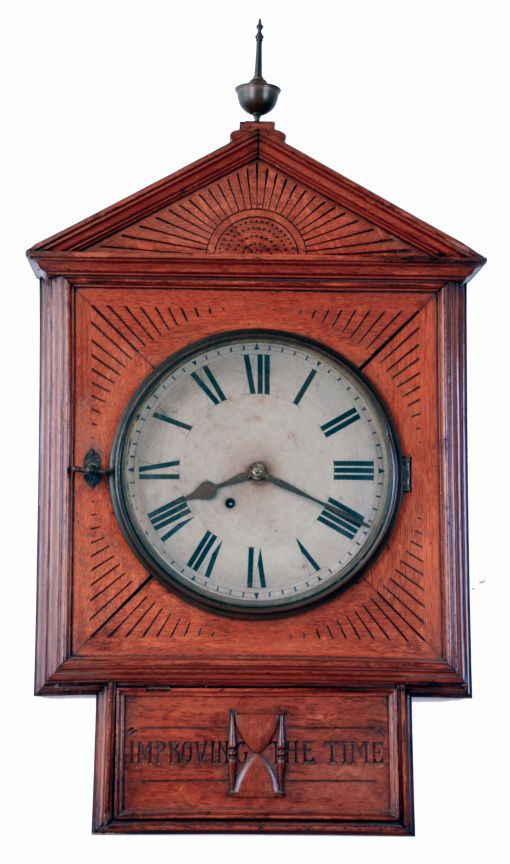 Folk Art wall clock, large, well made oak case with gabled facade, incised line carving, ogee and astragal moldings, and hinged access panel for pendulum with applied, carved hourglass, and also carved "Improving The Time", top with brass finial, Roman numeral paper dial, spade and poker hands, 8 days spring driven, timepiece movement by Ansonia, case dated in pencil on back, 1882