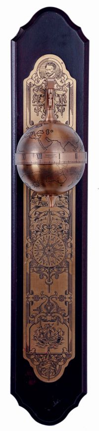 Thwaites & Reed, England for the Franklin Mint, Sir Francis Drake model falling ball gravity clock. The spherical, weighted, engraved brass case containing the 8 day timepiece movement, and with annular time display, suspended from a bracket affixed to a wall mounted board, with engraved ornamental brass back plate, c1980