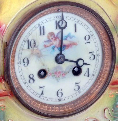 England, Strasburg Ware clock, with French movement, colorful earthenware case, enamel scene with figures in a landscape below the dial, Arabic numeral white enamel dial with putto and floral festoon, the case resting on its original Strasburg Ware base, 8 days, time and strike movement, c1920