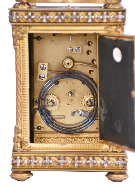 France, for Bailey, Banks & Biddle Co., Philadelphia, a very decorative striking carriage clock with original travel case, the gilt case with green onyx panels, top and base with gilt fret, the frets, handle and bezel set with brilliants, Arabic numeral white enamel dial with polychrome enamel floral garlands, gilt Louis XV style hands, 8 day, time and strike movement with lever platform counting the hours in passing, together with its original leather covered travel case and key