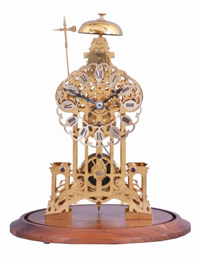 England, signed Smith, Clerkenwell, c1890 chain fusee pub movement, now in a modern skeletonized frame representing Brighton Pavilion, the frame appearing to have been cut on an EDM wire machine, and then polished by hand. The silvered dial is nicely fretted and the Roman Numerals are sharply engraved and black filled. The frame surmounted by a bell that is struck once on the passing of each hour. Covered by a round glass dome and mounted on a turned walnut base.