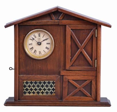 F. Kroeber Clock Co., New York, "Mountain Boy", 30 hour, time and alarm, spring driven brass movement in a walnut case resembling a cottage or barn with bisque figure of a boy urging the owner to rise.