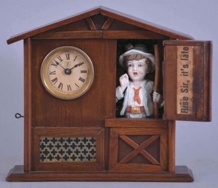 F. Kroeber Clock Co., New York, "Mountain Boy", 30 hour, time and alarm, spring driven brass movement in a walnut case resembling a cottage or barn with bisque figure of a boy urging the owner to rise.