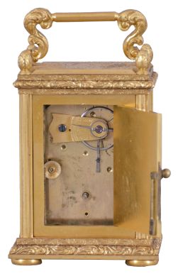 England, a very decorative miniature carriage timepiece, the gilt case with expertly engraved foliate ornament, the corners with reeded columns, surmounted by chased and engraved finials, the top with acanthus decorated handle, Roman numeral silvered dial with engraved center and gilt, engraved mask, blued steel Breguet style hands, 8 day timepiece movement with lever escapement, and spring barrel fixed to the front plate