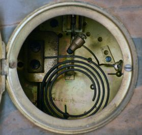 France, Green Onyx Figural Clock, with cream colored arabic numeral dial set within a brass bezel with beveled glass, patinated spelter young lady figure titled "Doux Retour" or Sweet Return celebrating the annual rite of spring with the figure holding a garland of flowers with a perched bird standing above the dial, green onyx multi-part case on cast and gilt classical feet, round eight day French time and strike, spring powered movement with coiled gong for hour strike and pendulum.