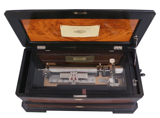 Mermod Freres, St. Croix, Switzerland, cylinder music box, with 4 eleven inch cylinders [3 fit in drawer built into case], each cylinder with 6 tunes. This is an ideal "Piccolo" format box, with tune number indicator, and Jacot "Safety Check", external crank wound, in an inlaid case with 45 degree corners. No tune sheets. WITH a non-matching but sturdy stained pine table from the same period with heavy turned legs.