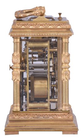 France, for Tiffany & Co., a Pillars style, petit sonnerie striking carriage clock with repeat, the glazed, gilt case with bright and matte surfaces, the base and cornice with cavetto and egg and dart moldings, the corners with acanthus decorated columns, and carrying handle also with foliate ornament, Arabic numeral white enamel dial with fretted, matte gilt foliate mask against a bright gilt background, blued steel distaff hands, 8 day time, strike, and alarm movement with lever platform, sounding petit sonnerie quarters in passing, with grand sonnerie repeating on demand, the base with strike/ silent lever